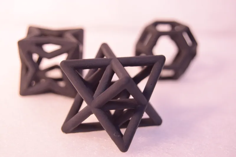 Three dark lattice parts: a star-shaped frame in front, two polyhedral frames behind